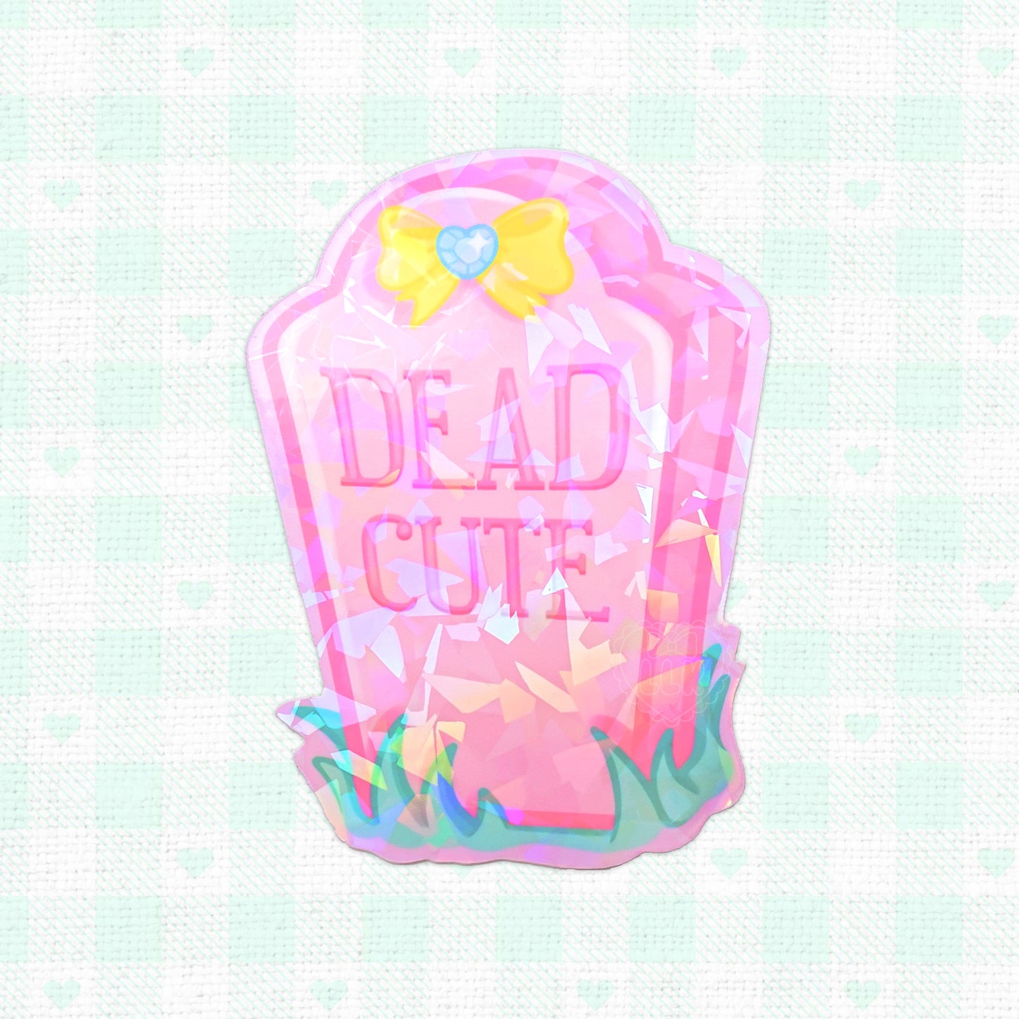 Holographic vinyl sticker of a pink tombstone labeled 'Dead Cute', decorated with playful designs, perfect for adding a unique touch to personal items.