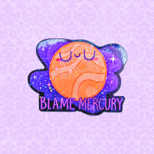 Colorful holographic vinyl sticker depicting a smiling planet Mercury with the phrase 'Blame Mercury', surrounded by stars, ideal for adding an astrological touch to any surface.