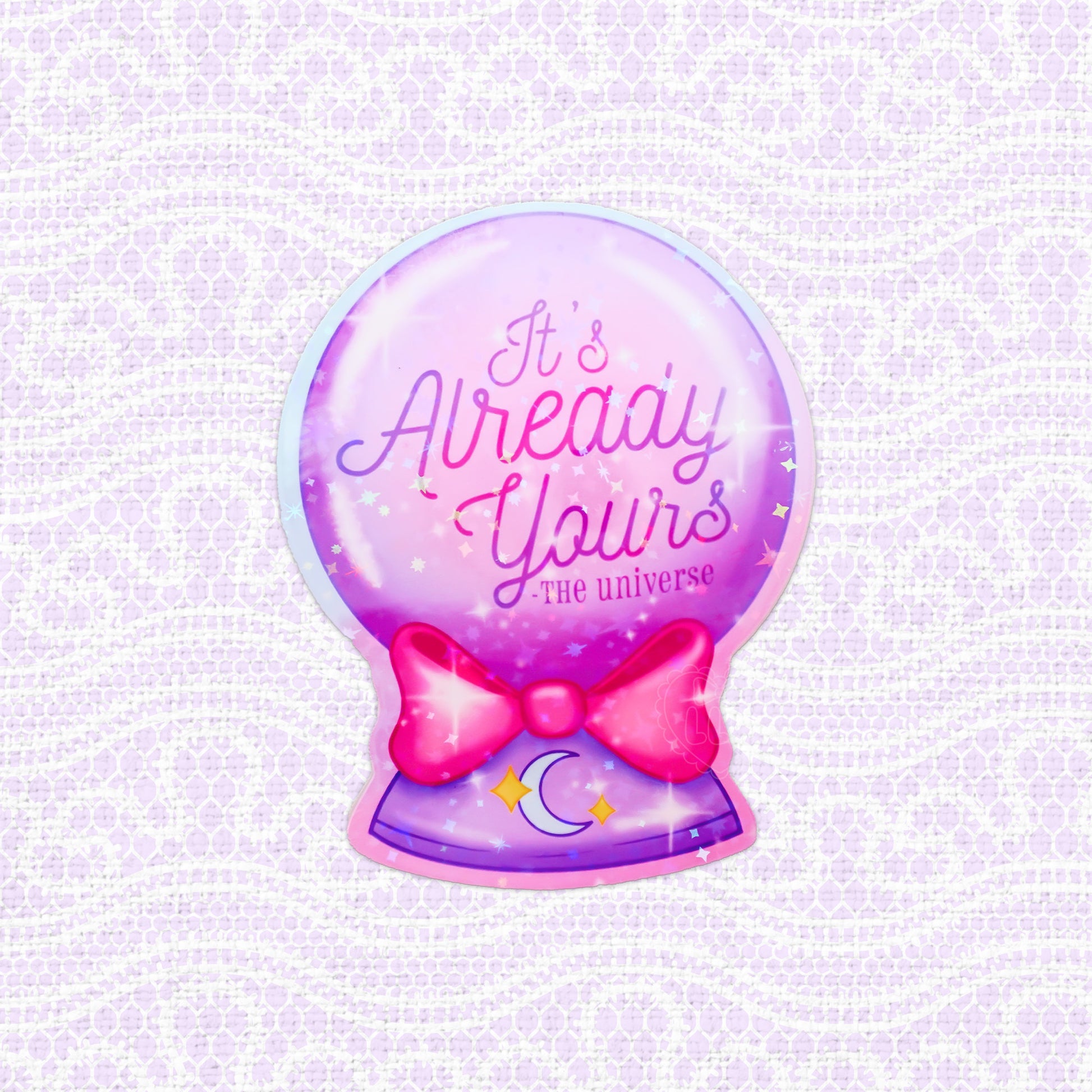 Holographic vinyl sticker of a crystal ball with the inspirational message 'It's Already Yours - The Universe', surrounded by stars and a bow, ideal for motivational decoration.