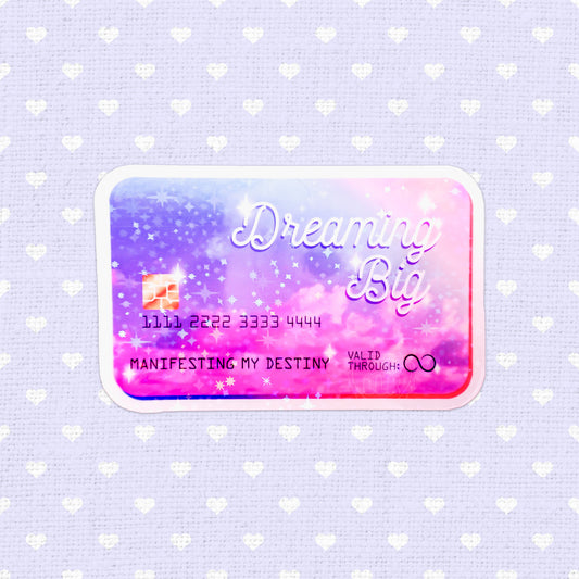 Holographic sticker designed as a credit card with the phrase 'Dreaming Big - Manifesting My Destiny', filled with vibrant colors and starry motifs, ideal for adding an inspirational touch to any item.