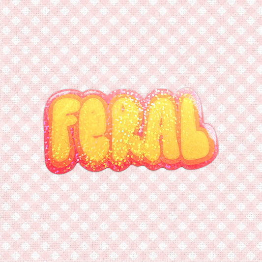 A holographic sticker with the word "Feral" in bold, glittery orange and red letters.