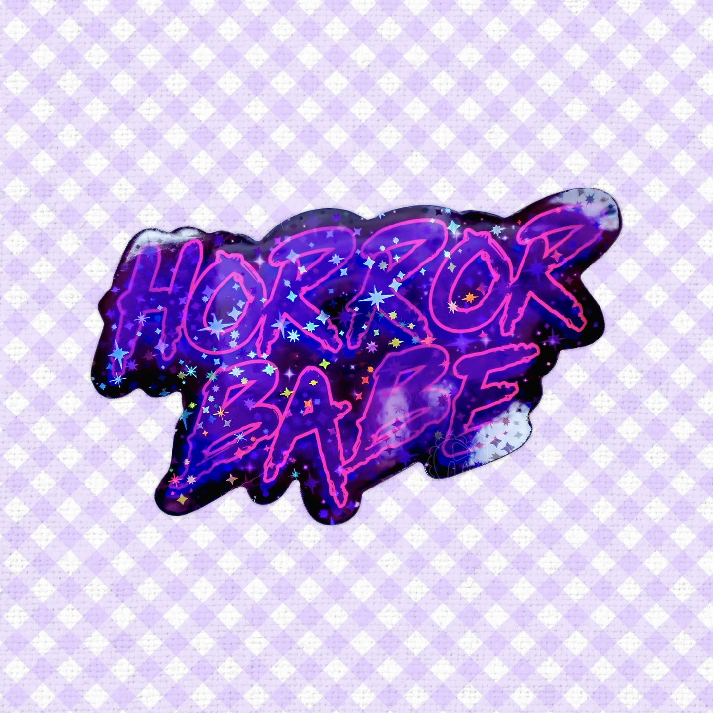 Holographic sticker of a text 'Horror Babe' with cosmic and starry details.